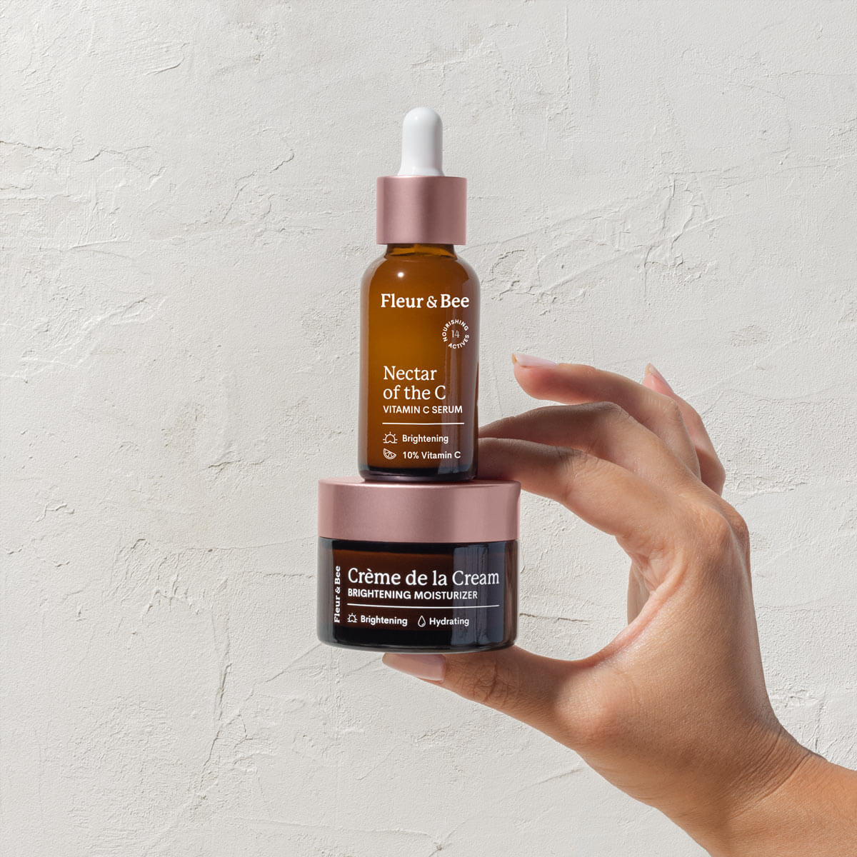 a hand holding Fleur & Bee's vegan vitamin c serum and brightening moisturizer