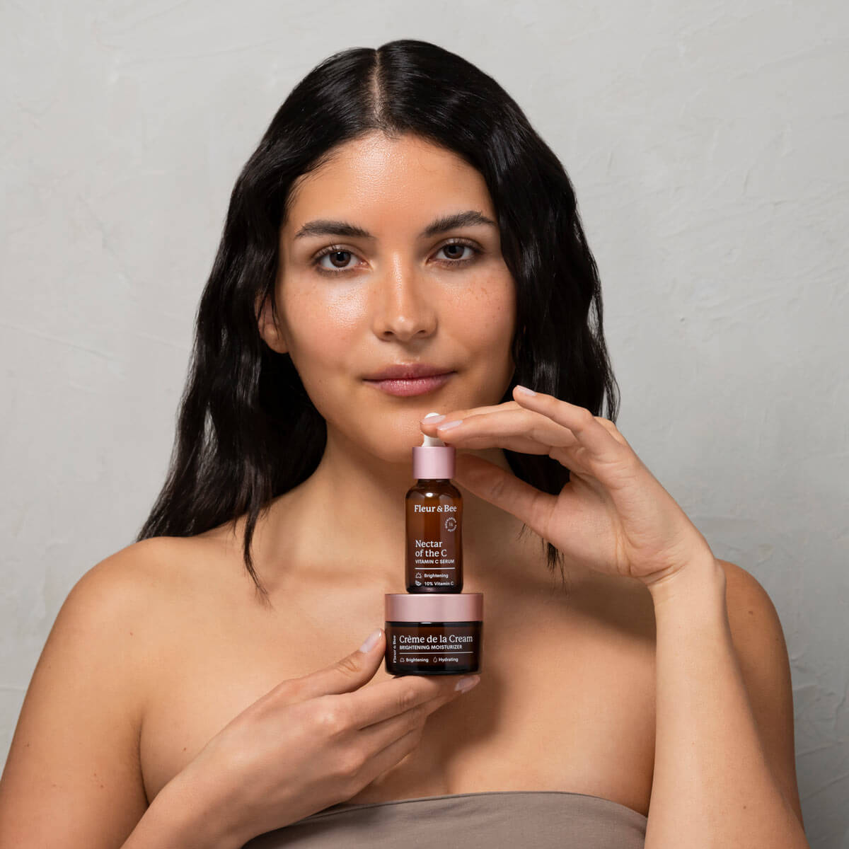 woman holding a vitamin c serum and brightening moisturizer