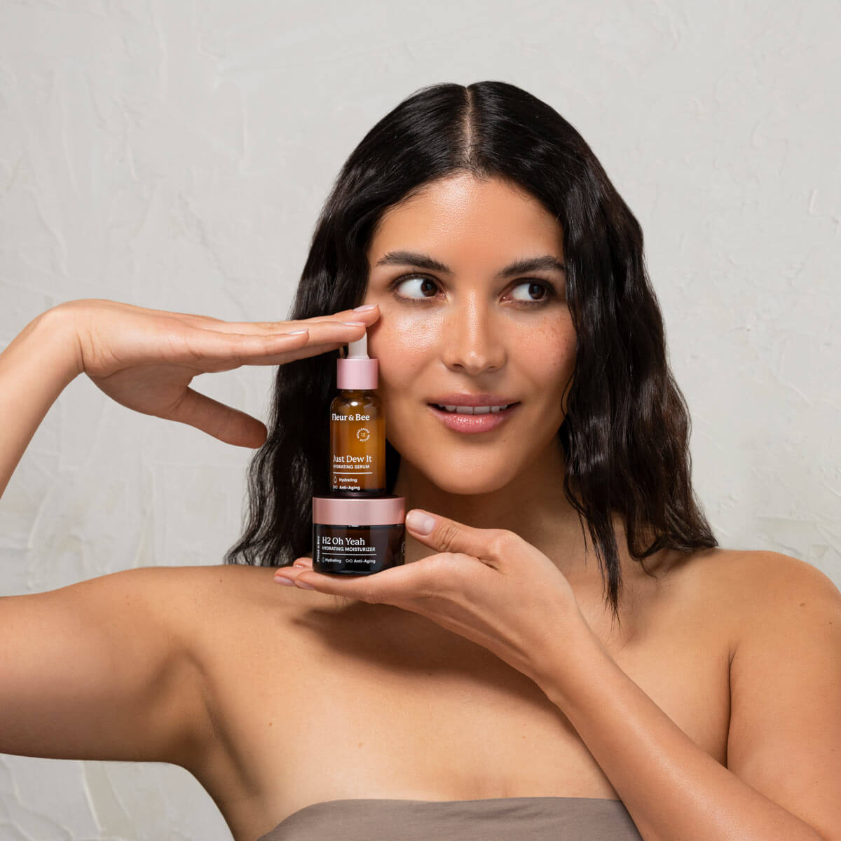 woman holding a hydrating moisturizer and hydrating serum