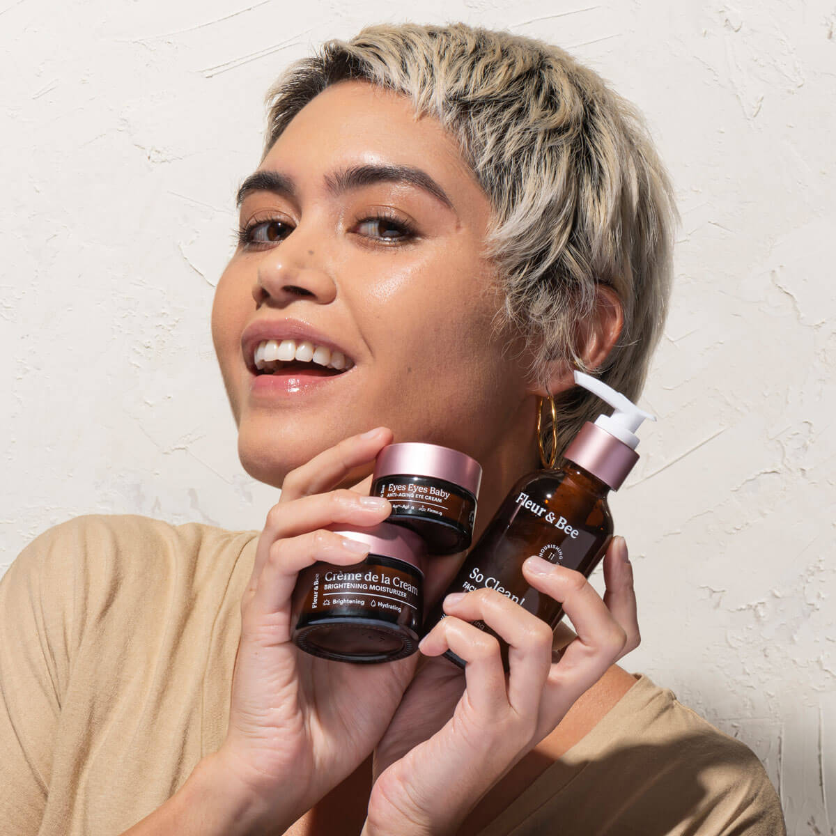 a woman holding three skincare products: a moisturizer, an eye cream, and a face wash